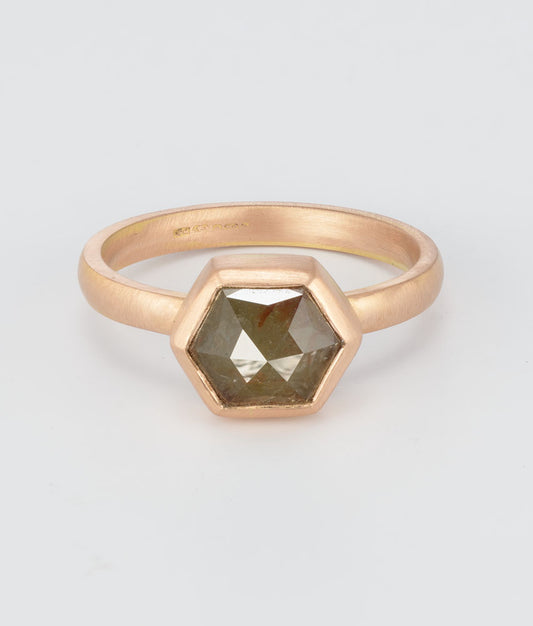 A rose gold ring with a hexagonal faceted gemstone, photographed on a clean light gray background.