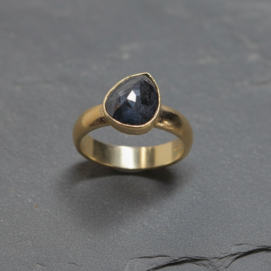 An 18ct yellow gold ring with a pear-shaped black rose cut diamond set in the center.