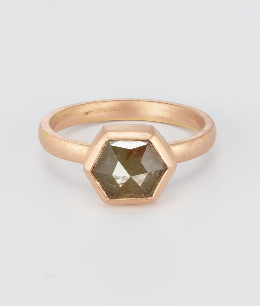 A rose gold ring with a hexagonal faceted gemstone, photographed on a clean light gray background.