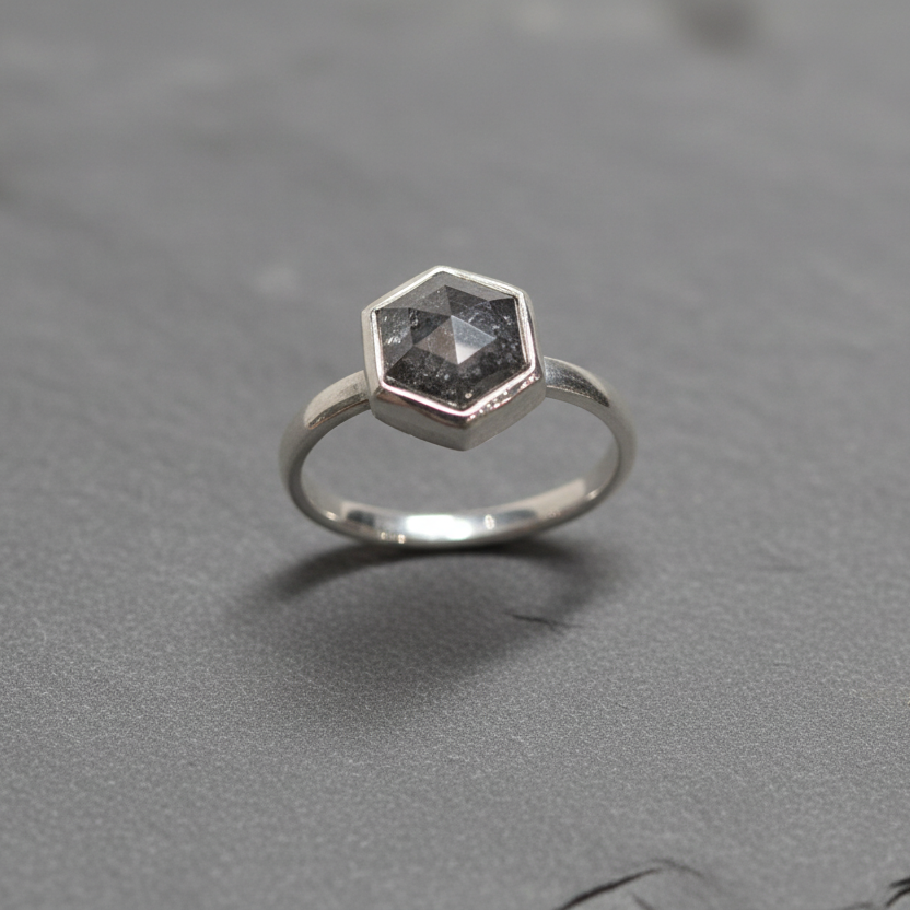 Silver ring with a hexagonal gemstone on a gray background