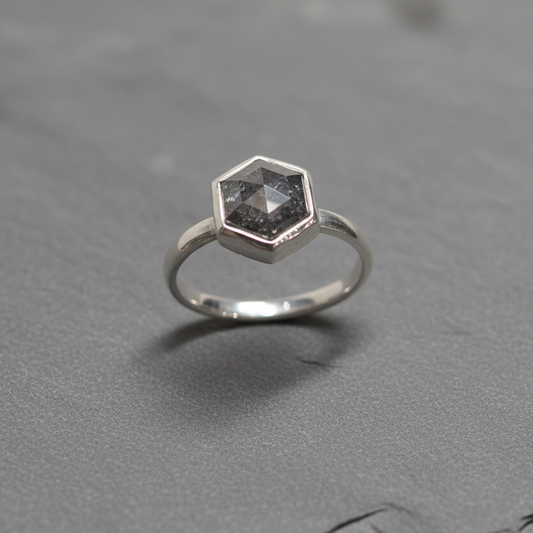 Silver ring with a hexagonal gemstone on a gray background